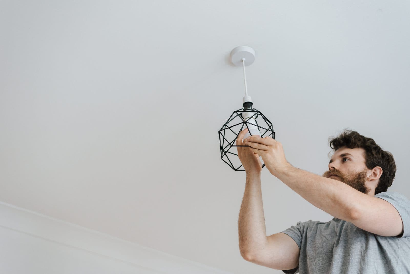 Electrician fitting a bulb into a ceiling light